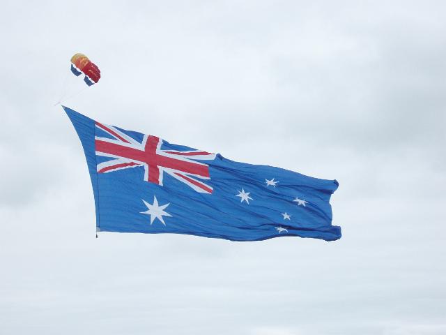 a large australian flag being towerd over sydney harbour on australia day