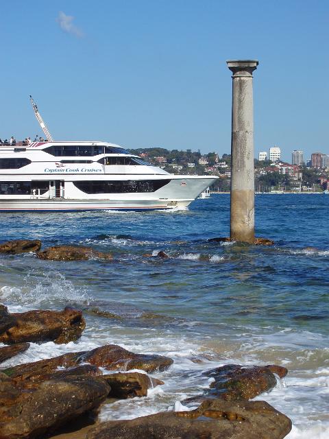 a large harbour cruise boat sailing past the old post office column, sydney harbour
