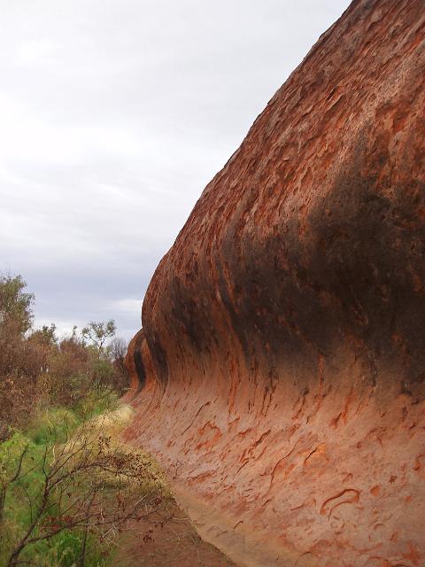 wind and sand eroded arkose sandstone shaped into the form of a wave at the base of uluru