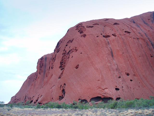 a view of uluru ayres rock showing the many caves around the base of the rock
