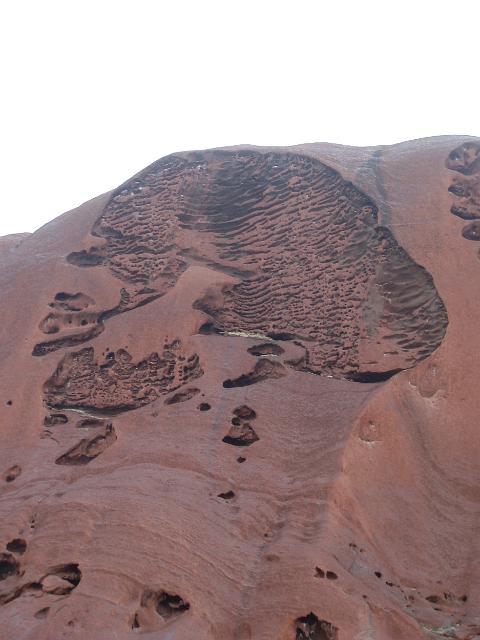 eroded rock on the side of uluru that looks like a head