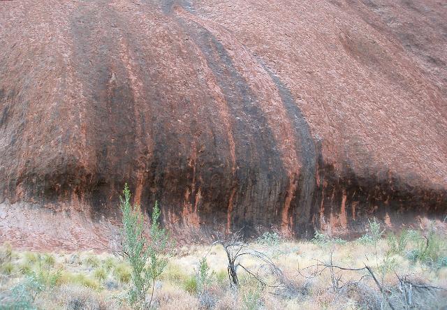 eroded rock at the base of uluru, shaped into a wave by wind blown sand