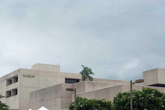 Exterior facade and flat roof design of the Queensland Art Gallery, Brisbane against a cloudy sky