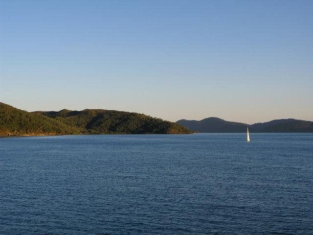 an idyllic sailing scene, a single boat sailing across the calm waters surrounding the whitsunday island group, queensland, australia