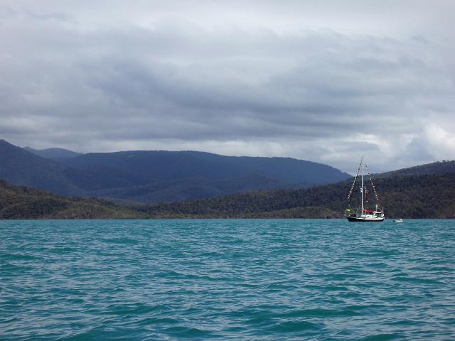 a sailing yacht with stays festooned with colorful flags