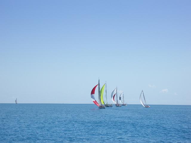 a yacht race in light air, several boats on a calm ocean flying spinnaker sails