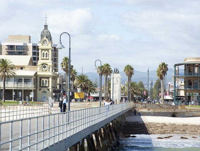 View from the pier at Glenelg, Adelaide, Australia looking back at historic heritage buildings with people standing on the promenade admiring the ocean