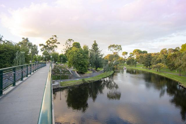 Bridge over a tranquil river with reflections of surrounding greenery in the Karrawirra Park , Adelaide, South Australia