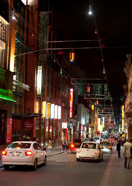 China Town, Melbourne, Australia with a view of the colourful neon lights in Little Bourke Street at night with passing traffic and pedestrians