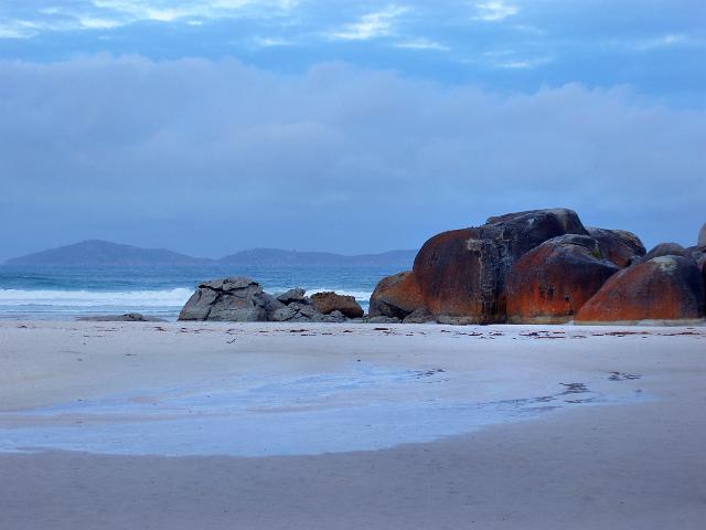 a dusk landscape at squeaky beach with oragne coloured rock contrasted in the blue light