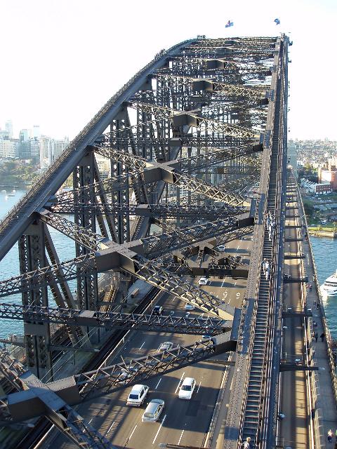 a view along the sydney harbour bridge with crossing traffic and pedestrians below