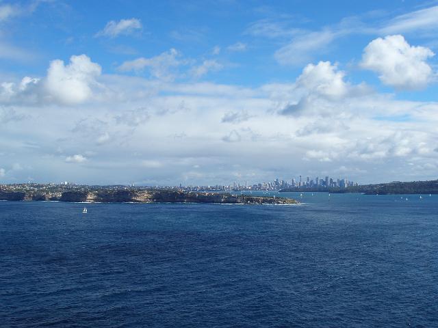 a wide angle image taking in a view of the sydney city skyline, the famous harbour and the hornby nighthouse on south head