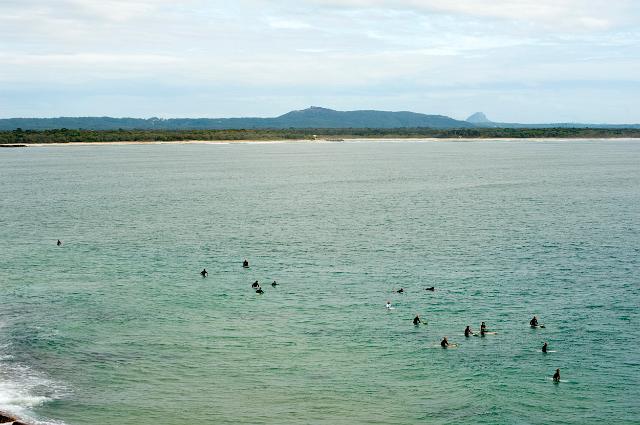 Group of surfers waiting on their boards at sea for a suitable wave off the beach at Noosa Beach in Queensland, Australia