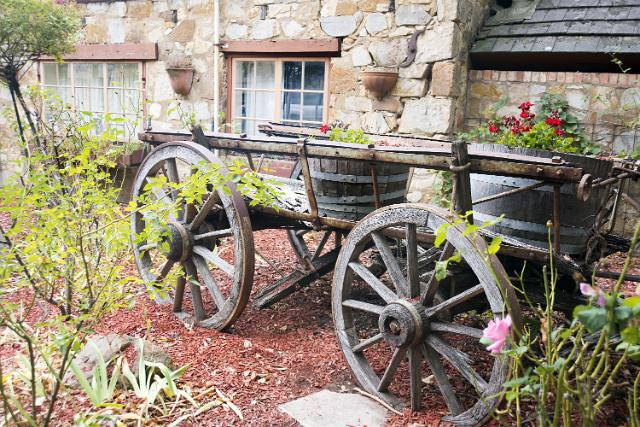 Decorative small wooden cart with barrels in a garden alongside an old stone building in Hahndorf, a town in South Australia with German origins