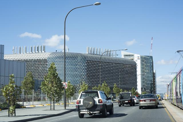 Streets of Adelaide, Australia with traffic on a dual lane highway passing modern high-rise buildings with tram tracks on the right
