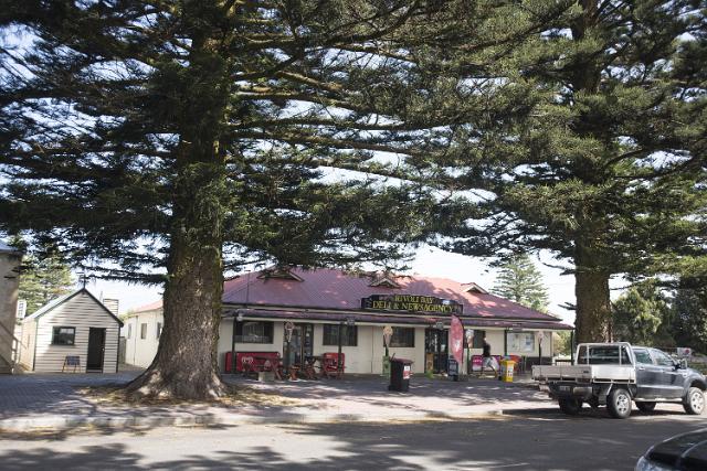 Historic heritage buildings in Beachport, South Australia in a street scene with quaint old store between two large pine trees