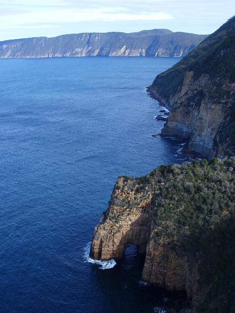 coastal vista featuring a rock arch on the tasman peninsula looking towards cape pillar